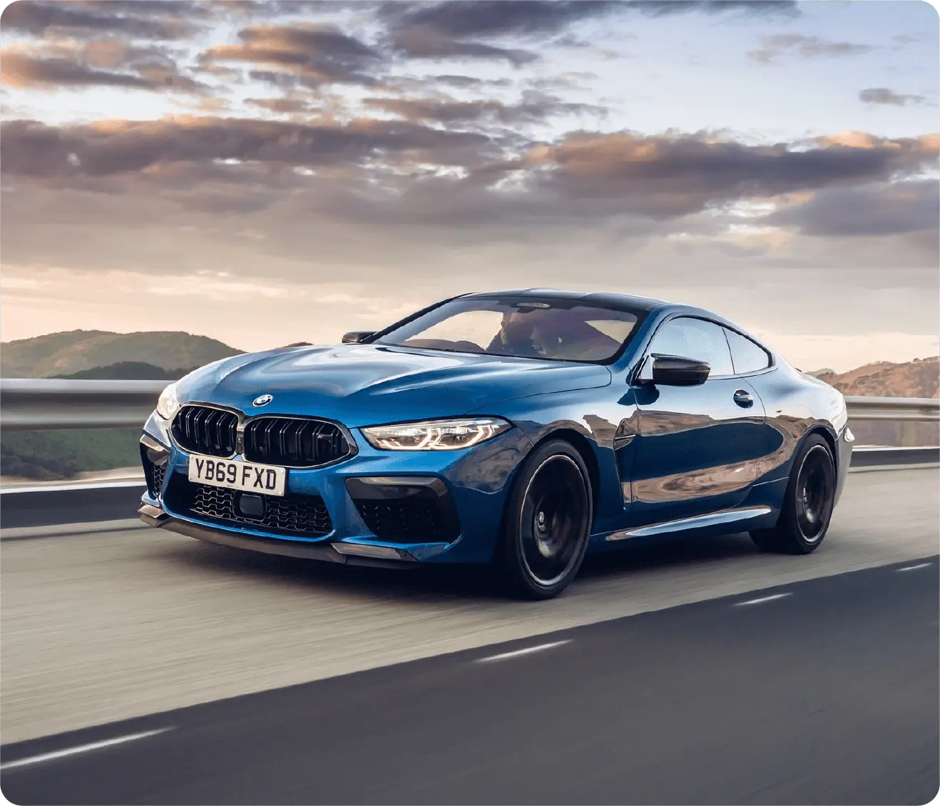 BMW driving on road with large hills in the background